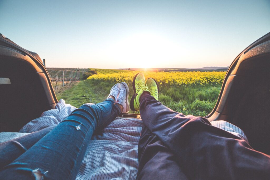 Point of view of a couple's legs in the bed of a truck, watching the sunset together, symbolizing a romantic and intimate moment