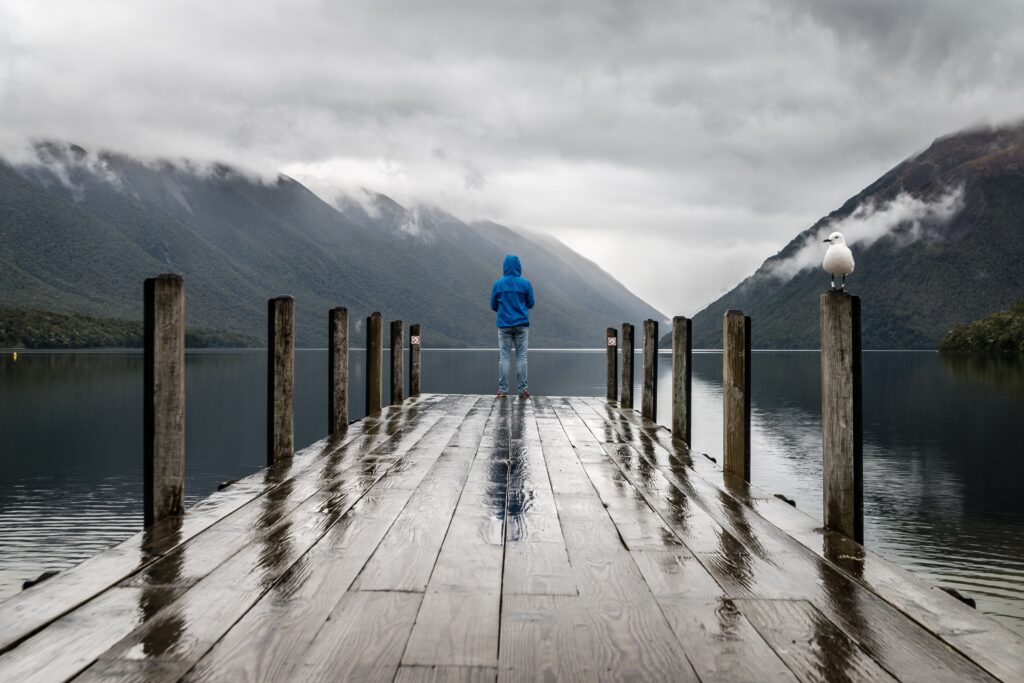 Man standing on a dock in the rain, representing perseverance and keeping a man’s interest