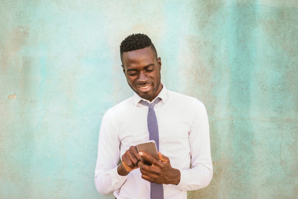 man-in-white-dress-shirt-holding-black-smartphone-smiling-3758101