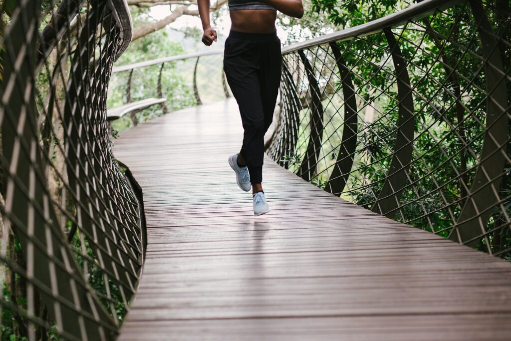 Woman running on a bridge in forest, demonstrating beginner workouts for women