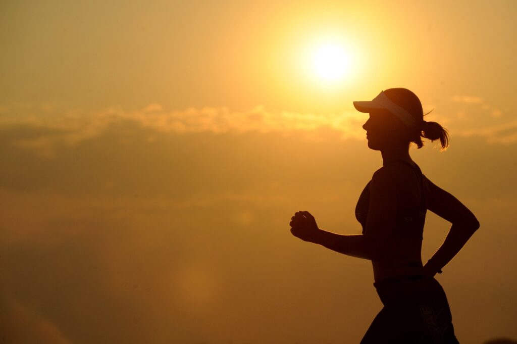 Woman jogging at sunset at high elevation, demonstrating how fitness can take attraction to new heights