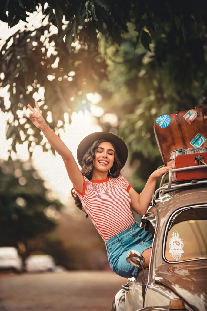 A smiling woman with her head out of a car window, enjoying the breeze and radiating joy and freedom